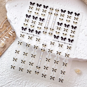 Autocollants de nail art nœuds double couche noir et or avec des détails raffinés