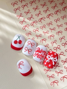 Macro detail of red and white bow design press-on nails with cherry art patterns