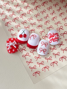 Detail of red and white press-on nails featuring 3D bows, cherry art and Alabama Shakes text