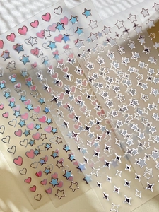 Close-up of holographic star and heart nail art stickers with gold foil details