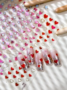 Detail of gold foil star and heart nail art stickers with pink gradient effects