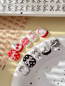 Detail of embossed bow nail art stickers with red cherry and black ribbon motifs
