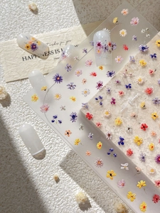 Detail of 3D embossed colorful wildflower nail stickers on translucent white nails