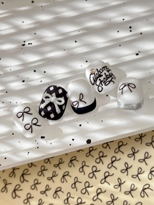 Detail of relief bow nail art stickers with black and white checkerboard and silver glitter