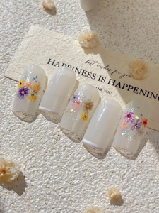 Detail of floral press-on nails with colorful flowers and white French tips on milky base