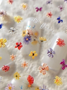 Macro shot of 3D embossed colorful wildflower nail stickers with detailed floral textures