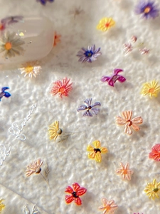 Macro detail of 3D embossed floral nail art stickers with colorful daisy patterns