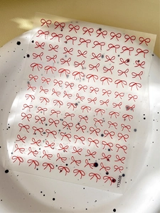 Detail view of YT5608 minimalist red bow nail art stickers on a decorative white plate