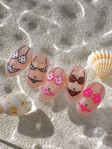 Détail de faux ongles sur le thème plage avec motifs bikini et décorations en strass