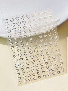 Macro detail of YT5811 gold heart nail stickers with metallic foil finish on white background