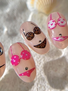 Détail de faux ongles amande avec motifs bikini et lunettes de soleil peints à la main