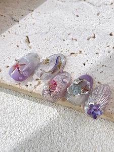 Dettaglio di adesivi per unghie 3D animali marini con perle e glitter su unghie viola