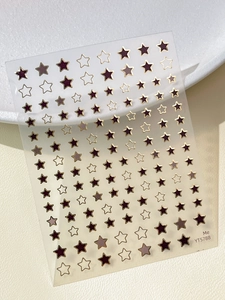 Macro shot of gold-stamped star nail stickers with solid and hollow designs in deep red and gray