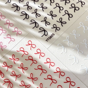 3D embossed bow nail art stickers in black, red, and white on a translucent base