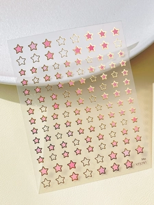 Macro detail of star nail art stickers with pink and gold foil constellation patterns