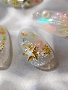Macro shot of 3D gold starfish and white pearls on glittery sea-themed nail stickers
