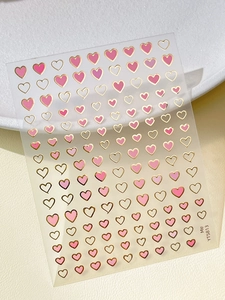 Close-up of pink and gold heart star nail art stickers on a textured leather background