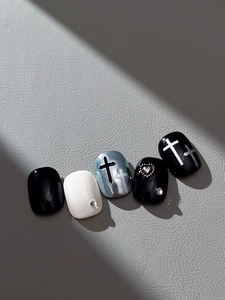 Detail of gothic press-on nails with embossed crosses and heart rhinestones on leather