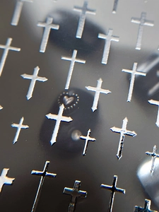 Macro detail of silver relief cross nail stickers with retro embossed textures