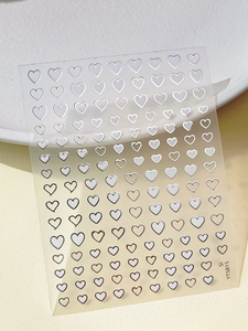 Close-up of silver heart-shaped nail stickers with metallic finish on transparent sheet