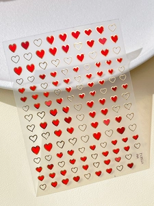 Detail of YT5812 heart nail art stickers with red and gold foil on beige texture