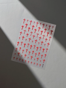 Macro detail of red embossed cross nail art stickers on a textured leather background
