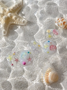 Dettaglio macro di decorazioni per unghie con piccole stelle marine e conchiglie in 3D