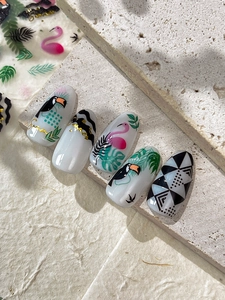 Detail of tropical press-on nails with flamingo, toucan and palm leaf motifs