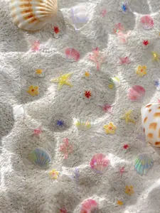 Dettaglio di adesivi per unghie a forma di stella marina su maglia bianca