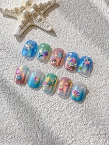 Macro shot of ocean theme nail art with pearlescent shells, starfish and 3D pearls