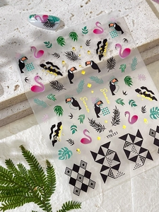 Macro view of tropical summer nail stickers with flamingos, toucans and golden palms