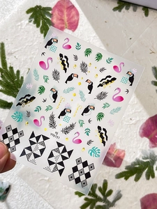 Macro detail of tropical nail stickers with flamingo and toucan patterns and Summer text