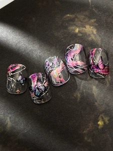 Détail de faux ongles noirs avec motifs de papillons irisés et lignes élégantes