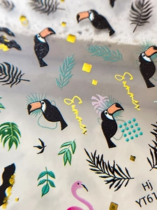 Macro shot of tropical nail art stickers featuring flamingo, toucan and palm leaf motifs
