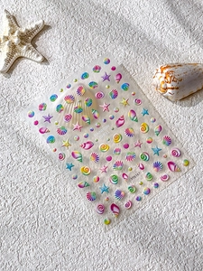 Close-up of 3D rainbow shell nail stickers with starfish motifs on beach textured background