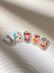 Macro shot of 3D strawberry cake nail art stickers with glitter and dessert charms