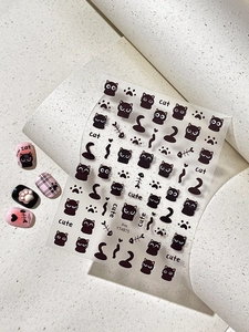 Detail of cute black cat nail art stickers featuring paw prints and fish bone patterns