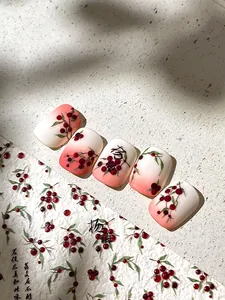 Makroaufnahme von rosa Ombré-Kunstnägeln mit roten Beeren und chinesischer Kalligraphie