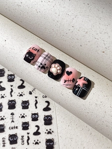 Close-up of pink and black cat nail charms with 3D paw prints and cute heart patterns