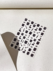 Detailed view of black cartoon cat nail stickers with paw prints and fish bones