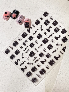 Close-up of black cartoon cat nail art stickers featuring fish bones and paw prints