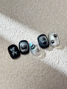 Detail of black cat theme press-on nails with silver cat-eye finish and punk stars