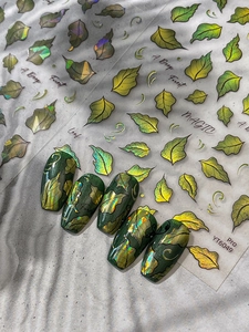 Detail of holographic leaf nail stickers in forest green and gold with English text