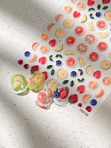 Macro shot of 3D embossed fruit nail stickers featuring lemon and strawberry patterns