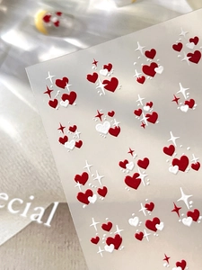 Macro detail of embossed nail stickers featuring red and white hearts with star patterns