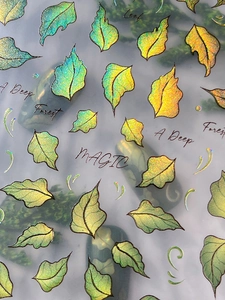 Close-up of laser aurora leaf nail stickers with Magic text and green gradient veins