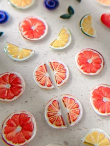 Detailed macro view of embossed resin fruit nail art charms with realistic lemon and leaf texture