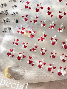 Macro detail of red and white embossed heart nail stickers with delicate star patterns