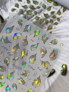 Macro shot of laser holographic leaf nail art stickers with deep forest design patterns