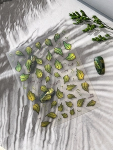 Detailed view of green metallic leaf nail art stickers with forest-themed leaf patterns